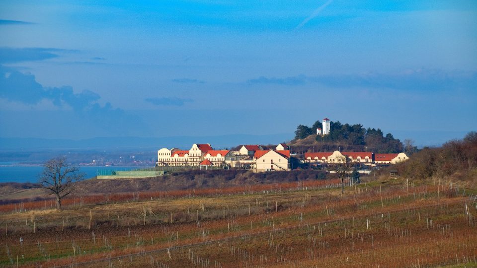 Pohled na vinařství a rozhlednu z východní strany. Na obzoru vlevo lze poznat oblaka páry, vycházející z chladicích věží dukovanské jaderné elektrárny